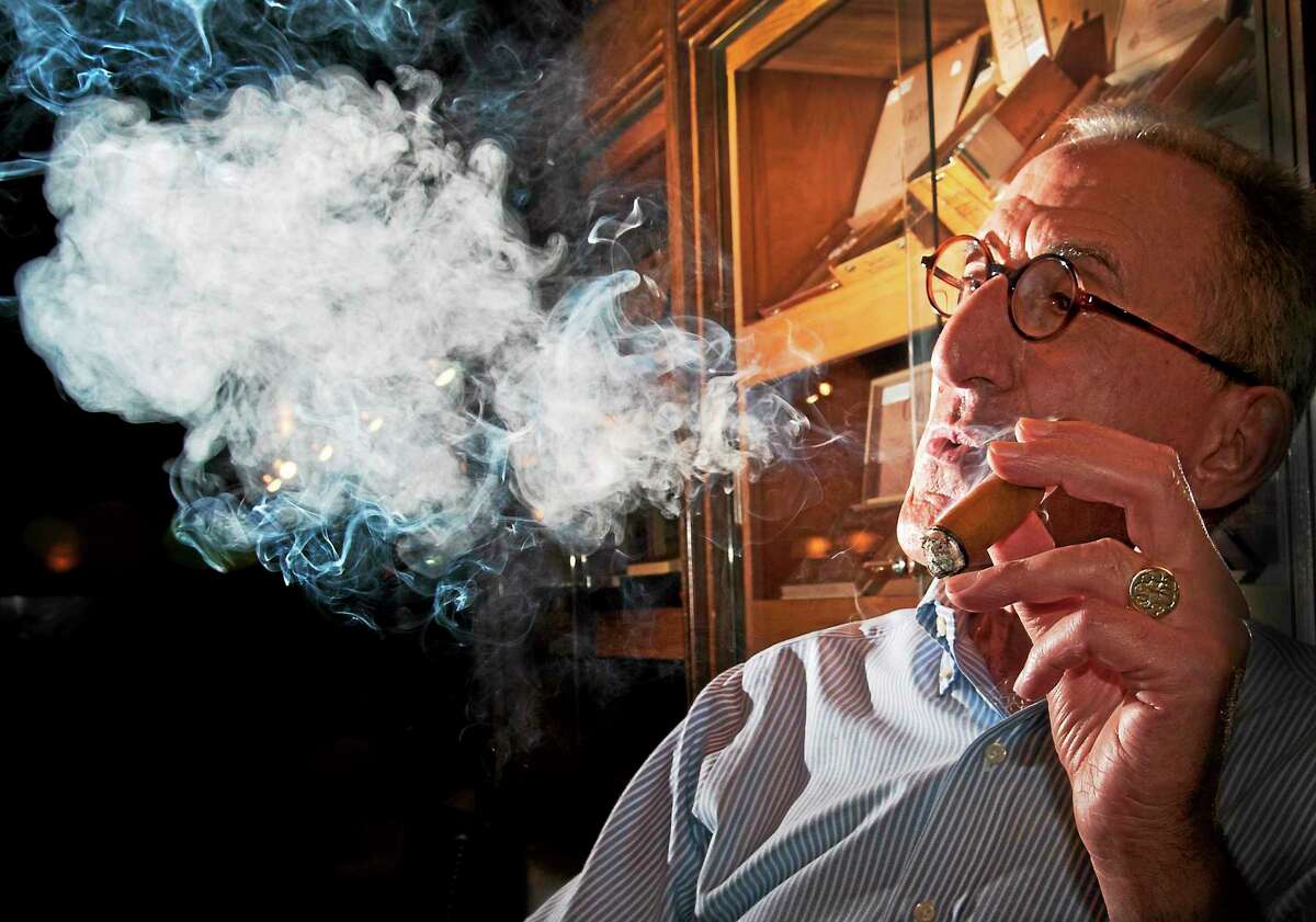 In this file photo from 2014, Joe Lentine enjoys one of his favorite cigars at the Owl Shop in New Haven. Lentine worked at the Owl Shop for 50 years. He died Thursday.