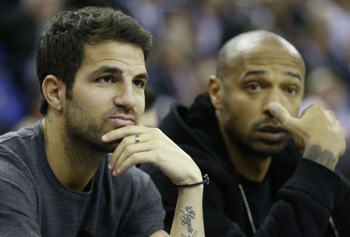 Chelsea soccer player Cesc Fabregas, left, and former Arsenal player Thierry Henry, right, watch the Milwaukee Bucks beat the New York Knicks on Thursday at the O2 Arena in London.