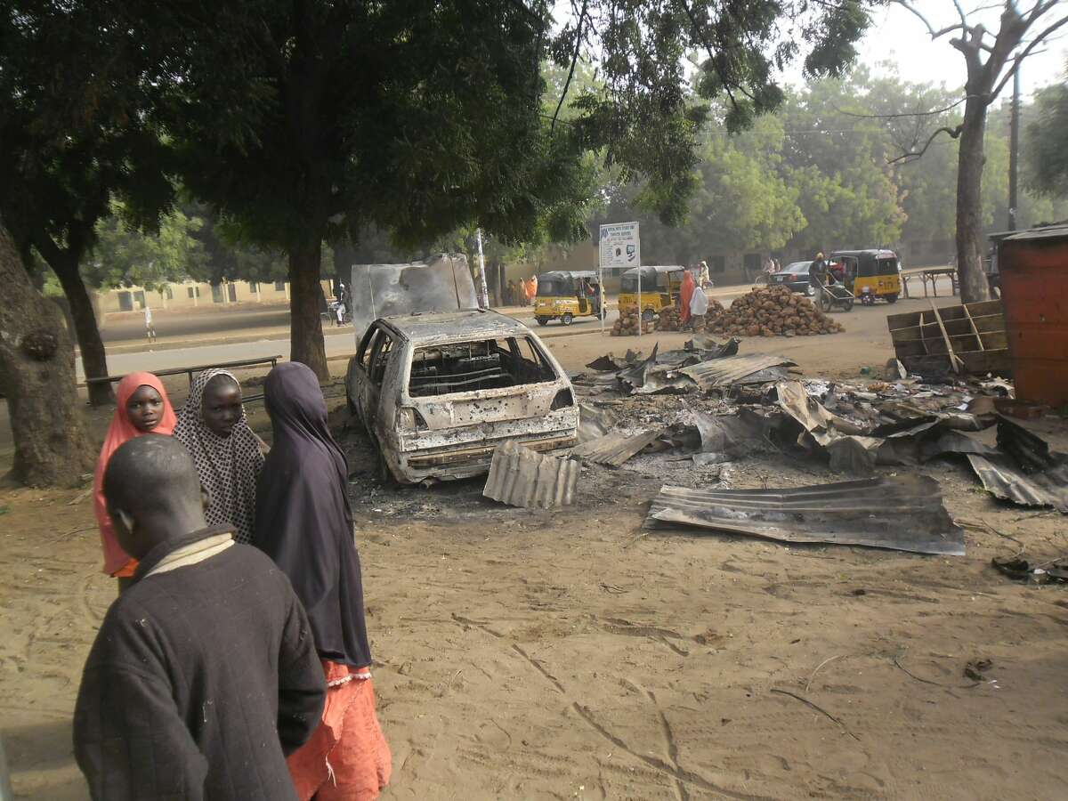 Children stand near the scene of an explosion in a mobile phone market in Potiskum, Nigeria on Jan. 12, 2015. Two female suicide bombers targeted the busy marketplace on Sunday.