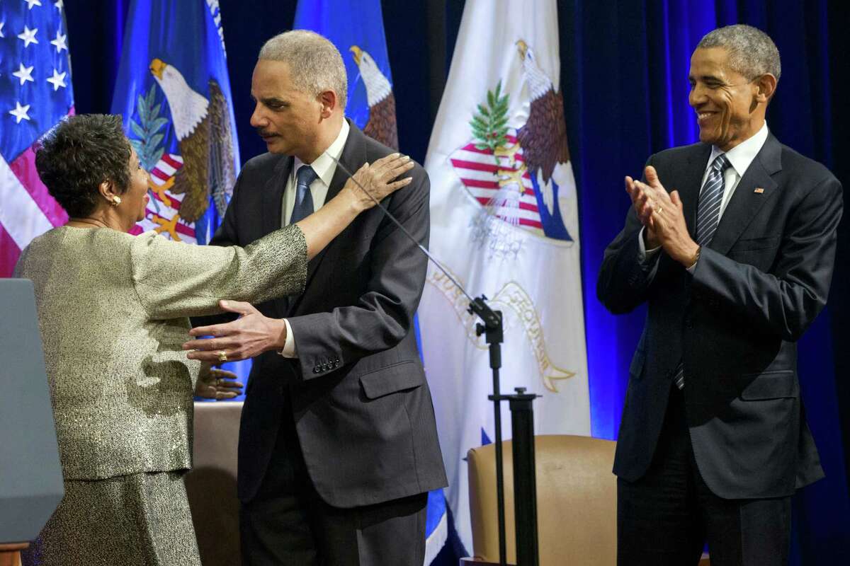 Singer Aretha Franklin, left, hugs outgoing Attorney General Eric Holder, as President Barack Obama applauds, at an event celebrating Holder at the Department of Justice in Washington on Feb. 27, 2015. Franklin.