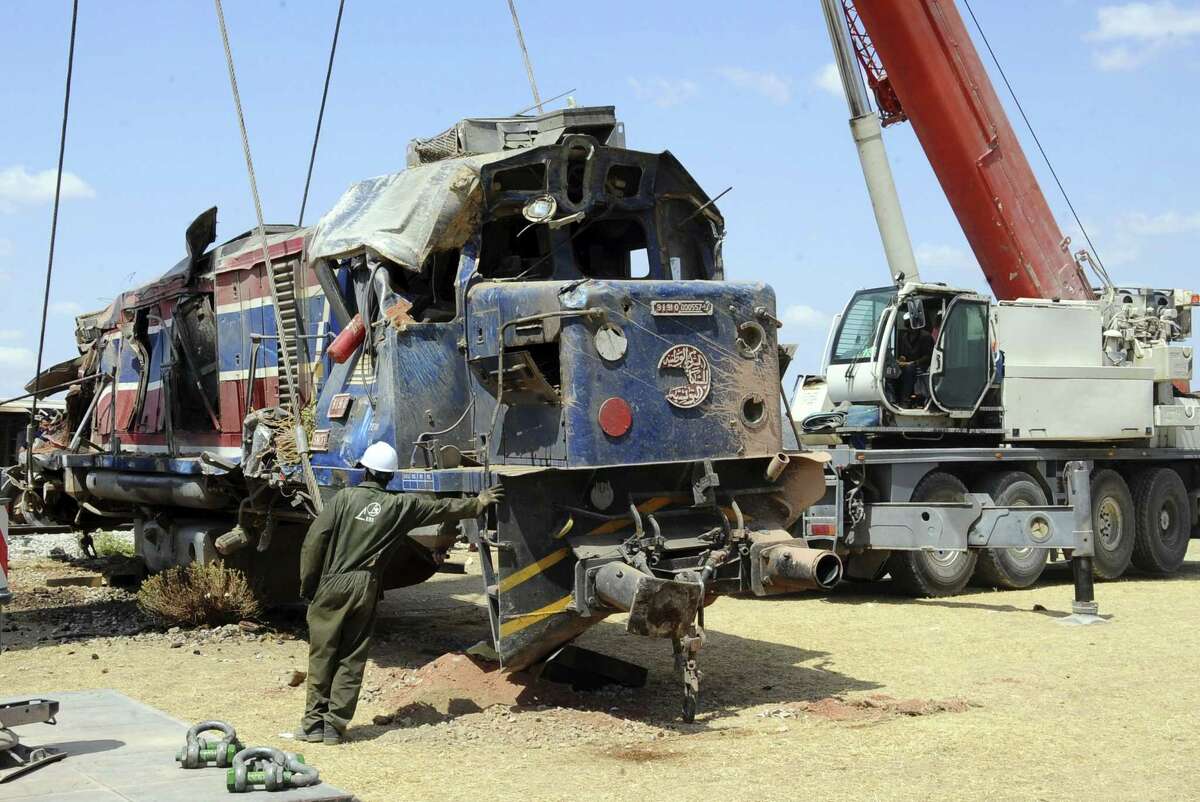 A workers helps removing the wreckage of a train of a train outside Fahs, 60 kilometers (37 miles) from Tunis, Tunisia, Tuesday, June 16, 2015. A Tunisian passenger train smashed into a semi-trailer truck southwest of the capital early Tuesday morning, killing more than a dozen people, according to authorities. (AP Photo/Hassene Dridi)