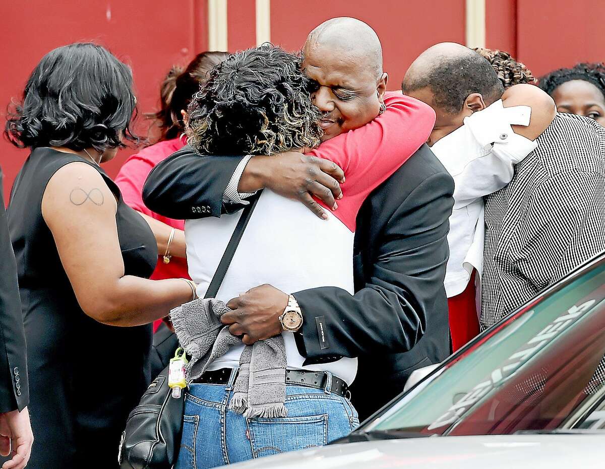 Michael Moore, center, father of Aleisha, 6, and Daaron, 7, is hugged outside Varick Memorial AME Zion Church before funeral services for the children Tuesday in New Haven.