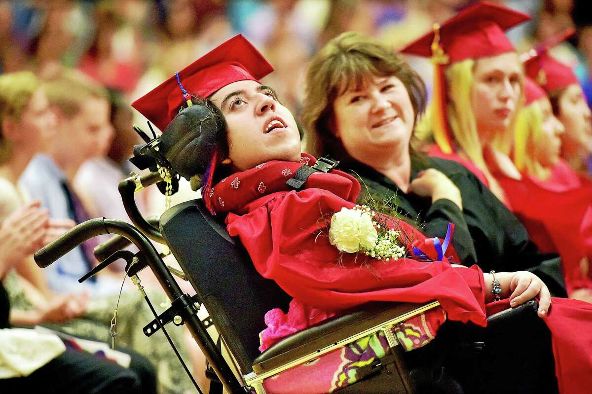 Paraprofessional Kacey Golebiewski looks over at Domenica “Mimma” DePaino, who has cerebral palsy, just a few minutes before taking DePaino up to receive her diploma at Joseph A. Foran High School in Milford, Tuesday.