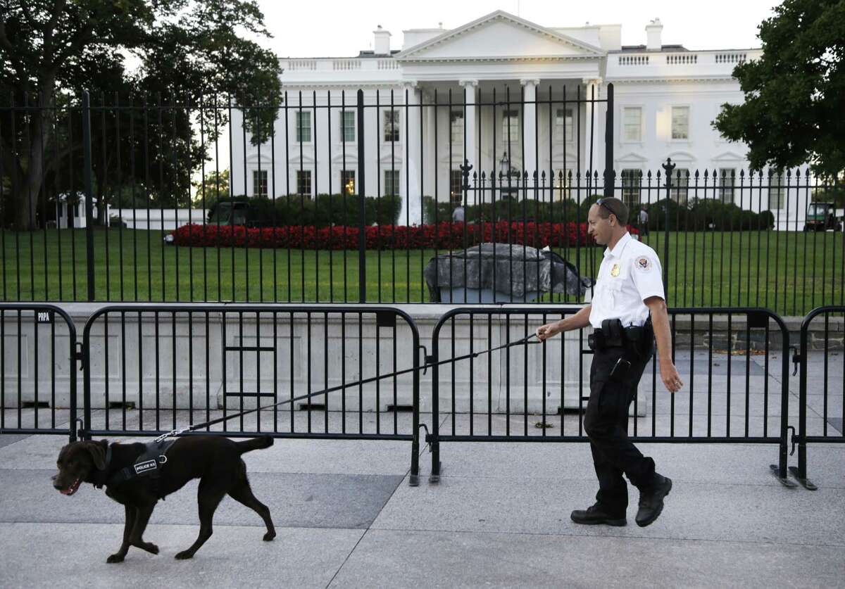 FILE - In this Sept. 22, 2014, file photo, a member of the Secret Service Uniformed Division with a K-9 walks along the perimeter fence along Pennsylvania Avenue outside the White House in Washington. Omar Gonzalez, 43, a knife-carrying Army veteran who scaled a White House fence and dashed into the executive mansion before being caught took a plea deal Friday, March 13, 2015. Gonzalez pleaded guilty to two federal charges. The Sept. 19 incident in which Gonzalez made it into the mansion's East Room preceded the disclosure of other serious Secret Service breaches in security for President Barack Obama and ultimately led to Julia Pierson's resignation as director of the agency. (AP Photo/Carolyn Kaster, File)
