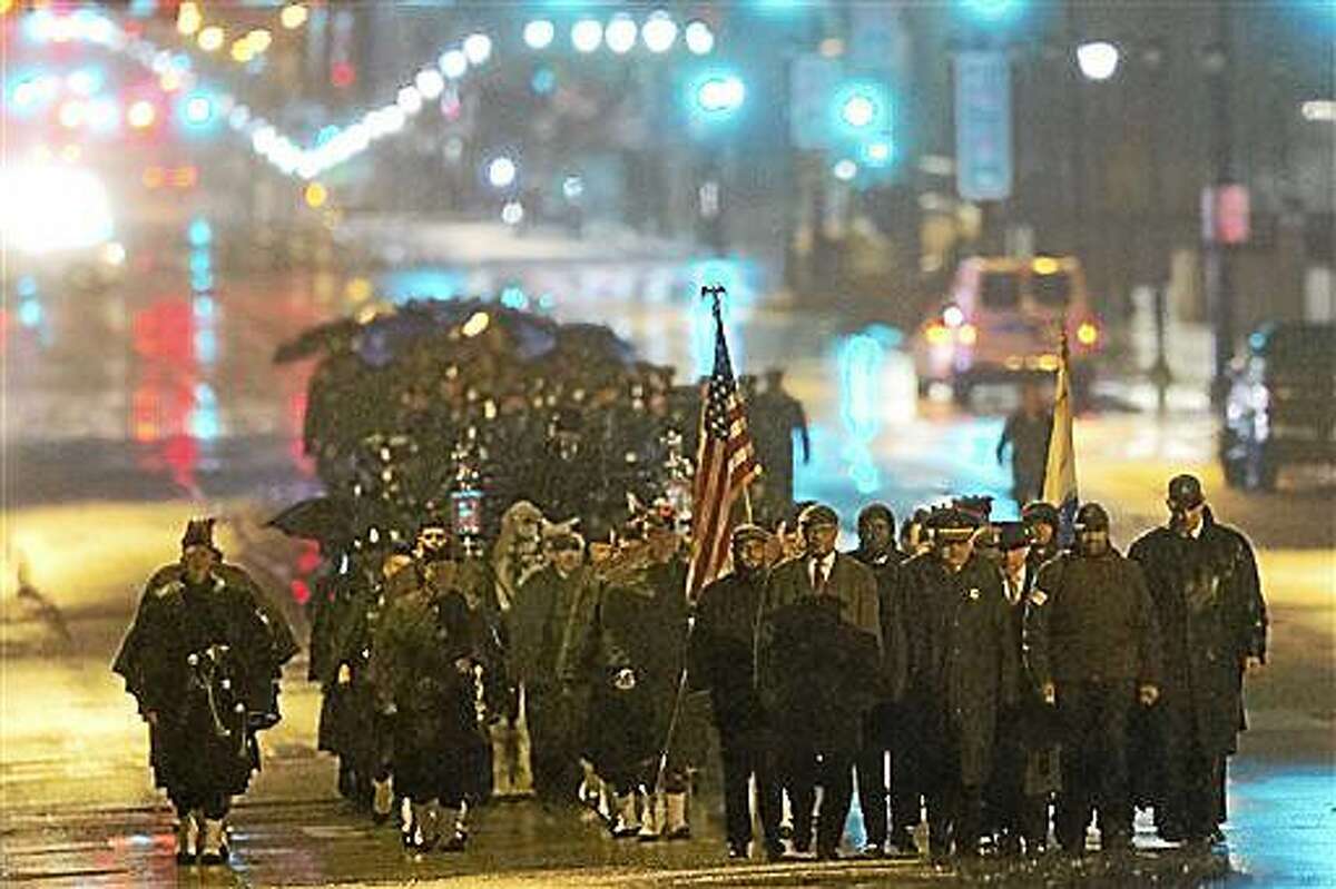 Philadelphia Police Officer Robert Wilson III funeral procession marches along Market Street during a winter rainstorm on Saturday, March 14, 2015, in Philadelphia. City officials said on March 5, 2015 Wilson was shot and killed after he and his partner exchanged gunfire with two suspects trying to rob a video game store. (AP Photo/Matt Rourke)