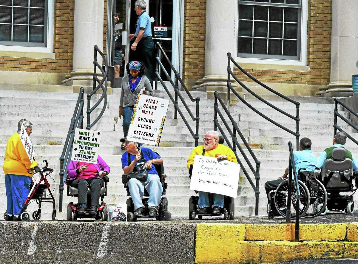 Irene Puccino of East Haven, left, president of the Center for Disability Rights board of directors, and Joe Luciano of Seymour, third from left, who helped organize the event, attend a rally outside the Seymour post office Wednesday.