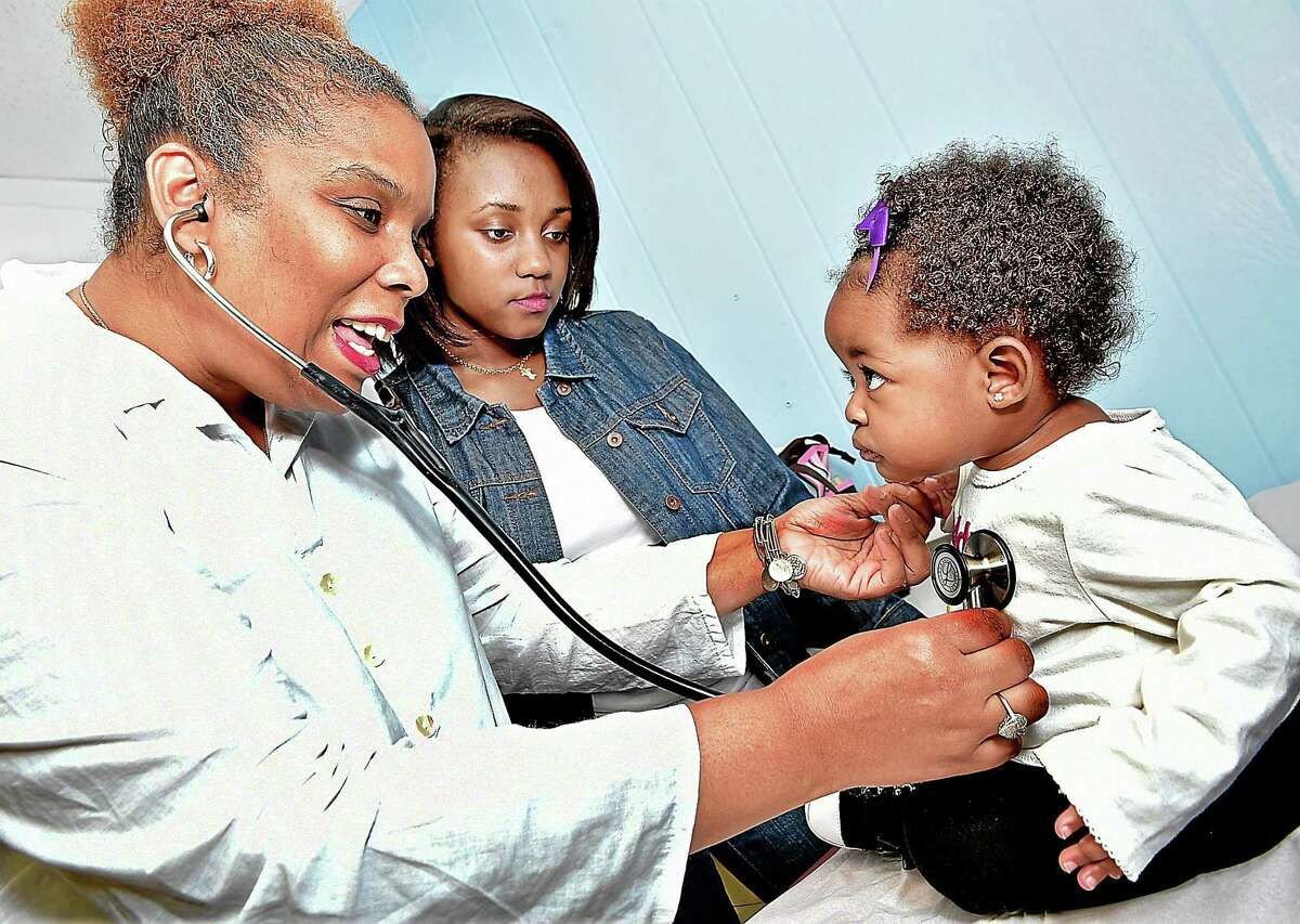 Dr. Tamiko Jackson-McArthur, of New Haven Pediatric & Adolescent Medical Services, Inc. at 1423 Chapel Street in New Haven, examines 7-month-old Maliya Madden. Briana Service, 15, a sophomore, is interning with Dr. Jackson-McArthur twice a week for three months as part of her leadership development class at Hillhouse High School. (Catherine Avalone/New Haven Register)