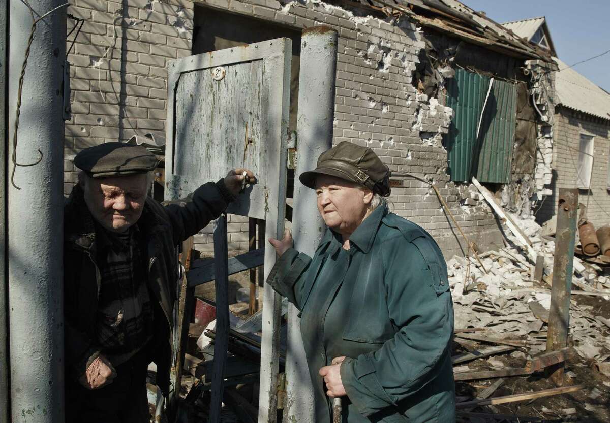 An elderly couple stand in front of their badly damaged house in Debaltseve, Ukraine, Monday, March 9, 2015. More than 6,000 people have died in eastern Ukraine since the start of the conflict almost a year ago that has led to a "merciless devastation of civilian lives and infrastructure," according to the U.N. human rights office. (AP Photo/Vadim Ghirda)