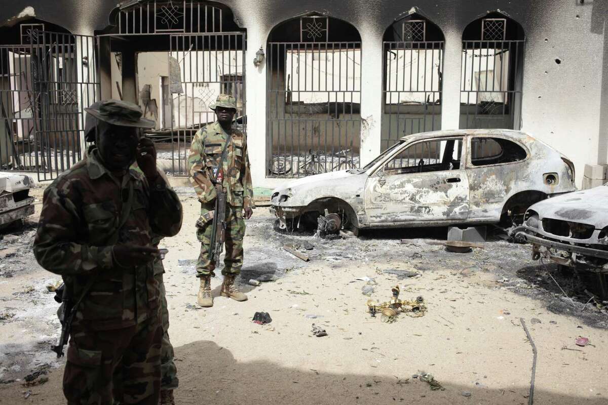 In this photo taken Wednesday, April 8, 2015, Nigerian soldiers stand guard in front of the burned out palace of the Emir of Gwoza, in Gwoza, Nigeria, a town newly liberated from Boko Haram. Each day brings new reports of atrocities, with mass graves being discovered in towns seized back from the militants who had set up a so-called ìIslamic caliphateî across a great swath of northeast Nigeria. Boko Haram's nearly 6-year-old Islamic uprising in northeast Nigeria that has killed thousands ó a reported 10,000 just last year ó and forced more than 1.5 million from their homes. (AP Photo/Lekan Oyekanmi)