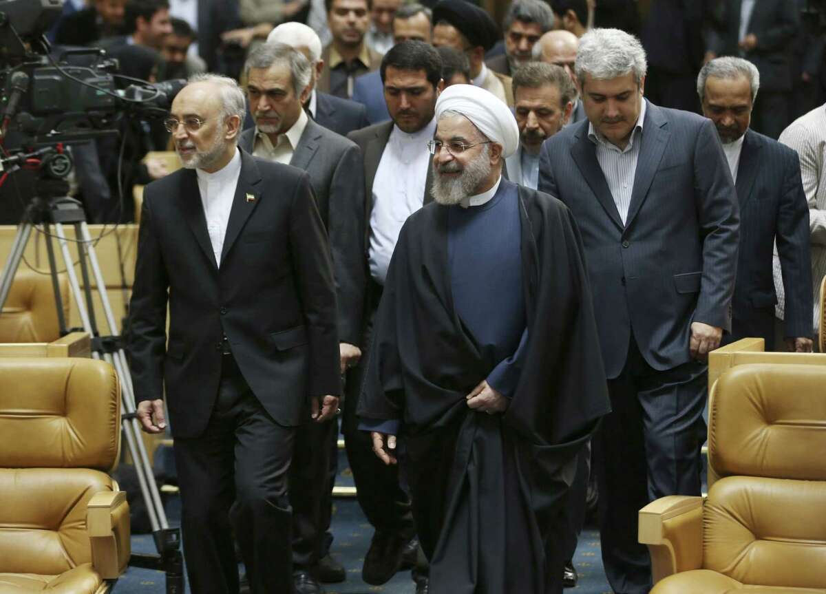 Iranian President Hassan Rouhani, center, arrives to attend a ceremony marking National Nuclear Technology Day, as he is accompanied by head of Iran's Atomic Energy Organization Ali Akbar Salehi, left, and Vice President for science and technology affairs Sorena Sattari, right, in Tehran, Iran, Thursday, April 9, 2015. Rouhani warned that Tehran will not sign on to a final nuclear deal with world powers unless it is predicated on the lifting of economic sanctions imposed on Iran over the controversial nuclear program. (AP Photo/Vahid Salemi)
