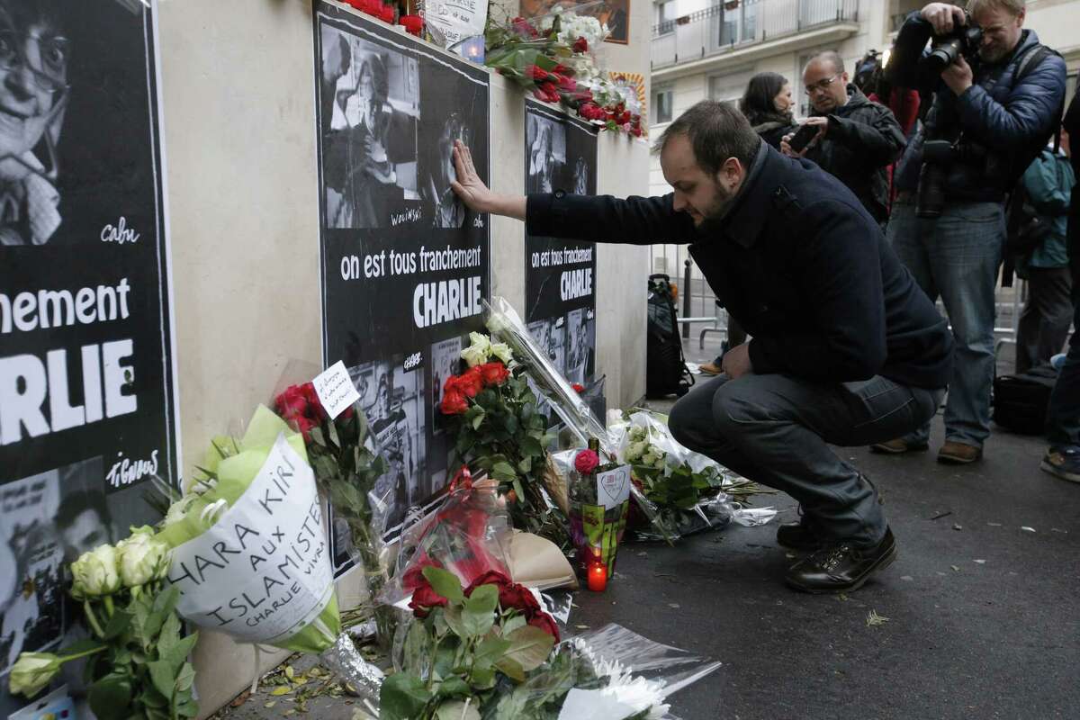 A man reacts as he squats down near flowers laying outside the Charlie Hebdo newspaper in Paris, Thursday, Jan.8, 2015, a day after masked gunmen stormed the offices of a satirical newspaper and killed 12 people. Protesters in some U.S. cities ó repeating the viral online slogan "Je Suis Charlie" or "I Am Charlie"ó demonstrated against the deadly terror attack on a Paris newspaper office, joining thousands around the world who took to the streets to rally against the killings. Poster reads: We really are all Charlie. (AP Photo/Francois Mori)