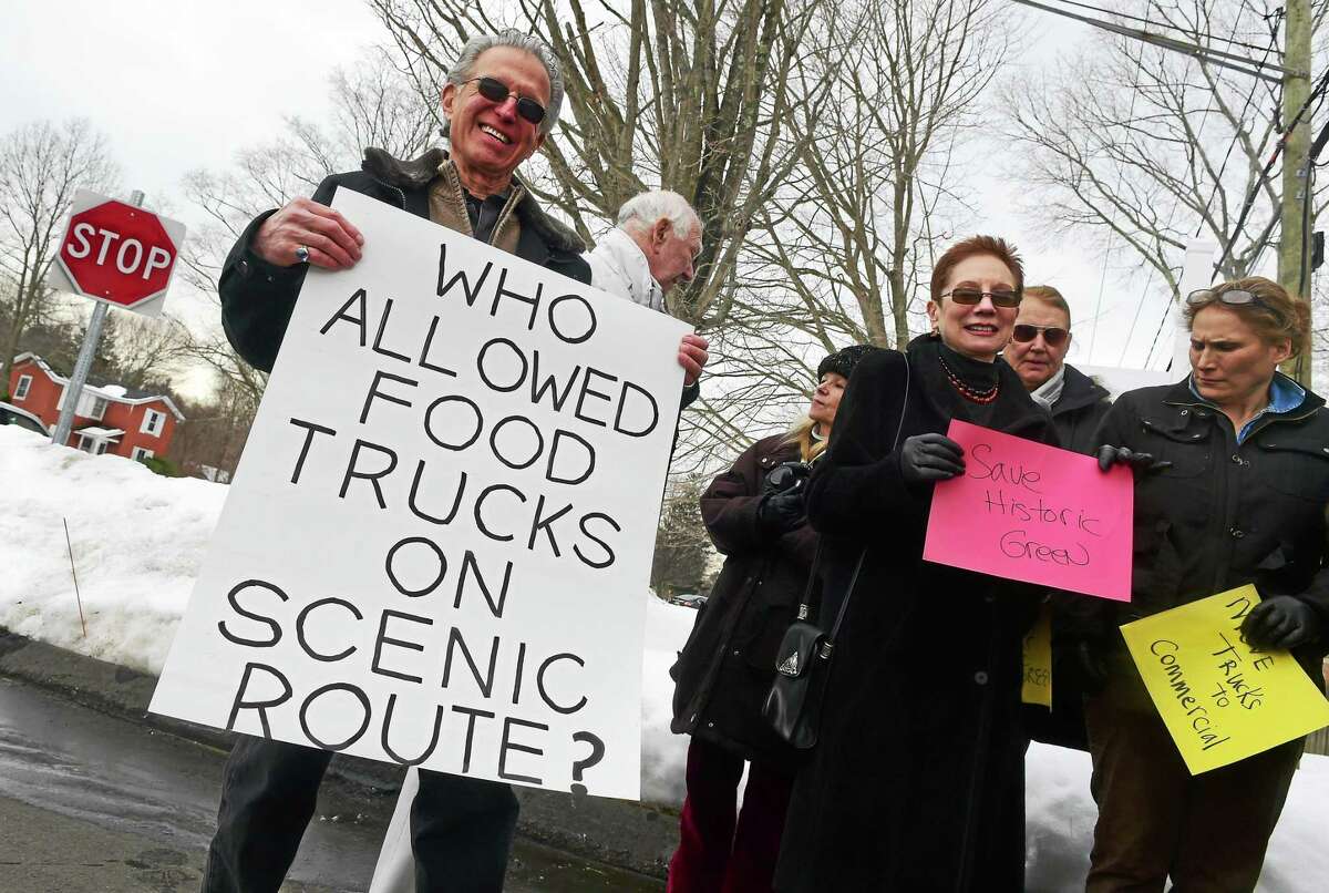Stuart Lerner of Madison, left, and approximately 20 people Sunday, standing in the Guilford Savings Bank parking lot on the edge of the Madison Green National Register Historic District, protest the presence of food trucks in the district.
