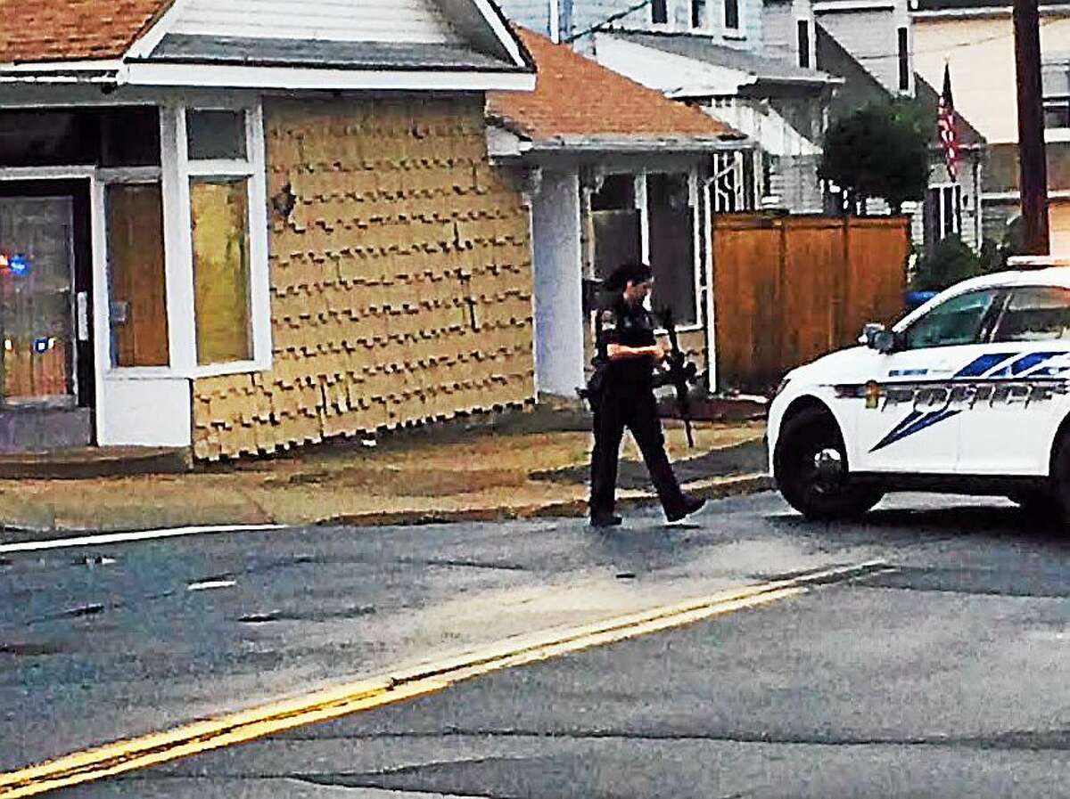A Wallingford police officer armed with an assault weapon positions herself behind a patrol car as SWAT team members search 51 Ward St. Tuesday afternoon.