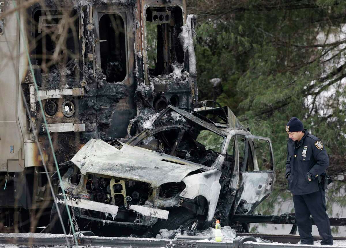 A police officer looks at an SUV that was crushed at the front of a Metro-North Railroad train Wednesday, Feb. 4, 2015, in Valhalla, N.Y. Five train passengers and the SUVís driver were killed in Tuesday eveningís crash, about 20 miles north of New York City. Authorities said the impact was so forceful the electrified third rail came up and pierced the train.