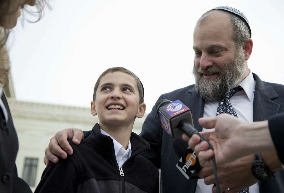 In this Nov. 3, 2014 photo, Menachem Zivotofsky and his father Ari Zivotofsky speaks to media outside the Supreme Court in Washington. The Supreme Court has struck down a disputed law that would have allowed Americans born in Jerusalem to list their birthplace as Israel on their U.S. passports.
