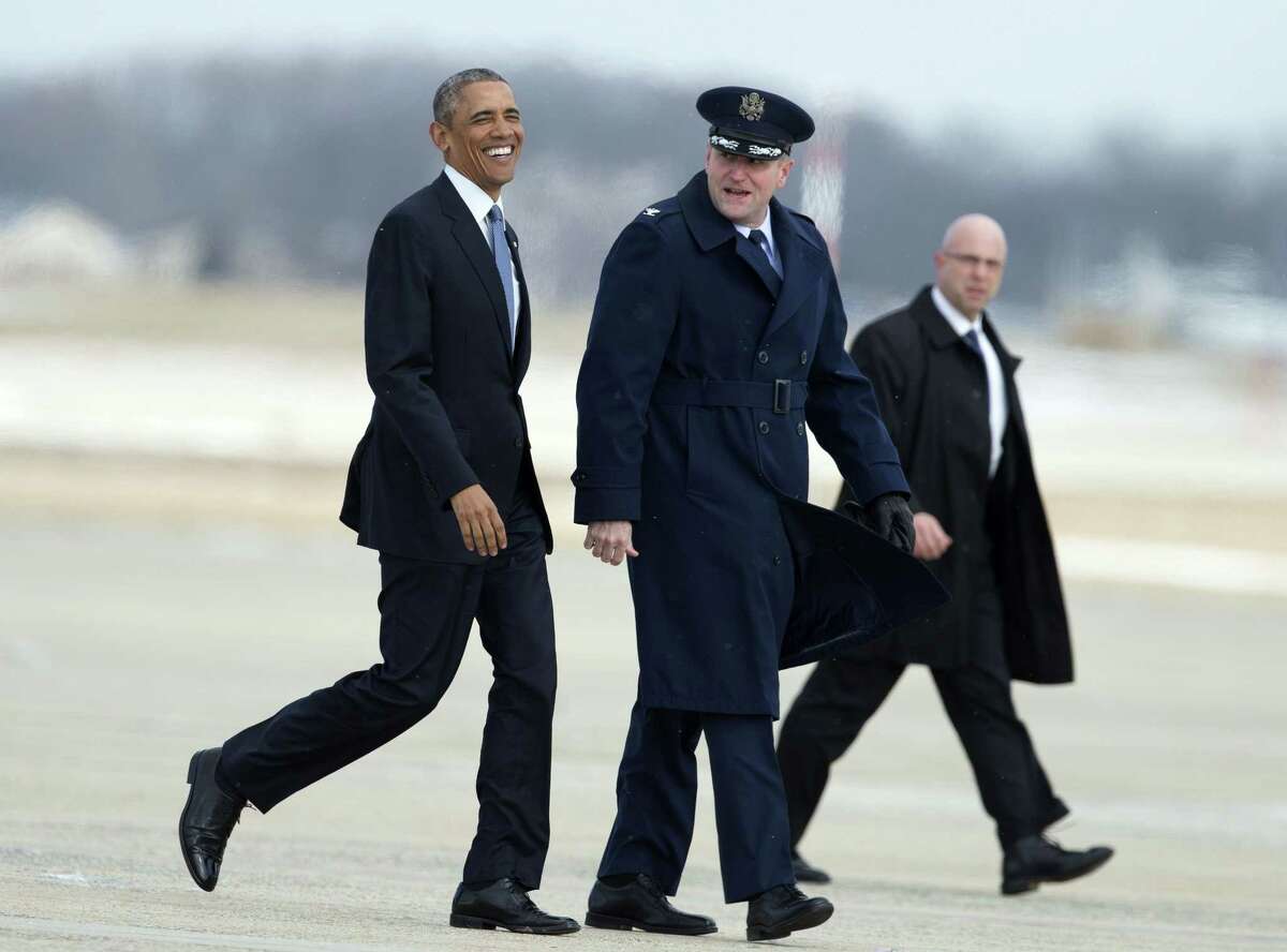 President Barack Obama, accompanied by 89th Airlift Wing Commander Col. John Millard, smiles as they walk on the tarmac at Andrews Air Force Base, Md., Wednesday, Jan. 7, 2015, as the president transferred from Marine One to Air Force One for a trip to Wayne, Mich. The president will speak at the Ford Michigan Assembly Plant to highlight the workers in the resurgent American automotive and manufacturing sector. Walking on the back right is an unidentified Secret Service agent.
