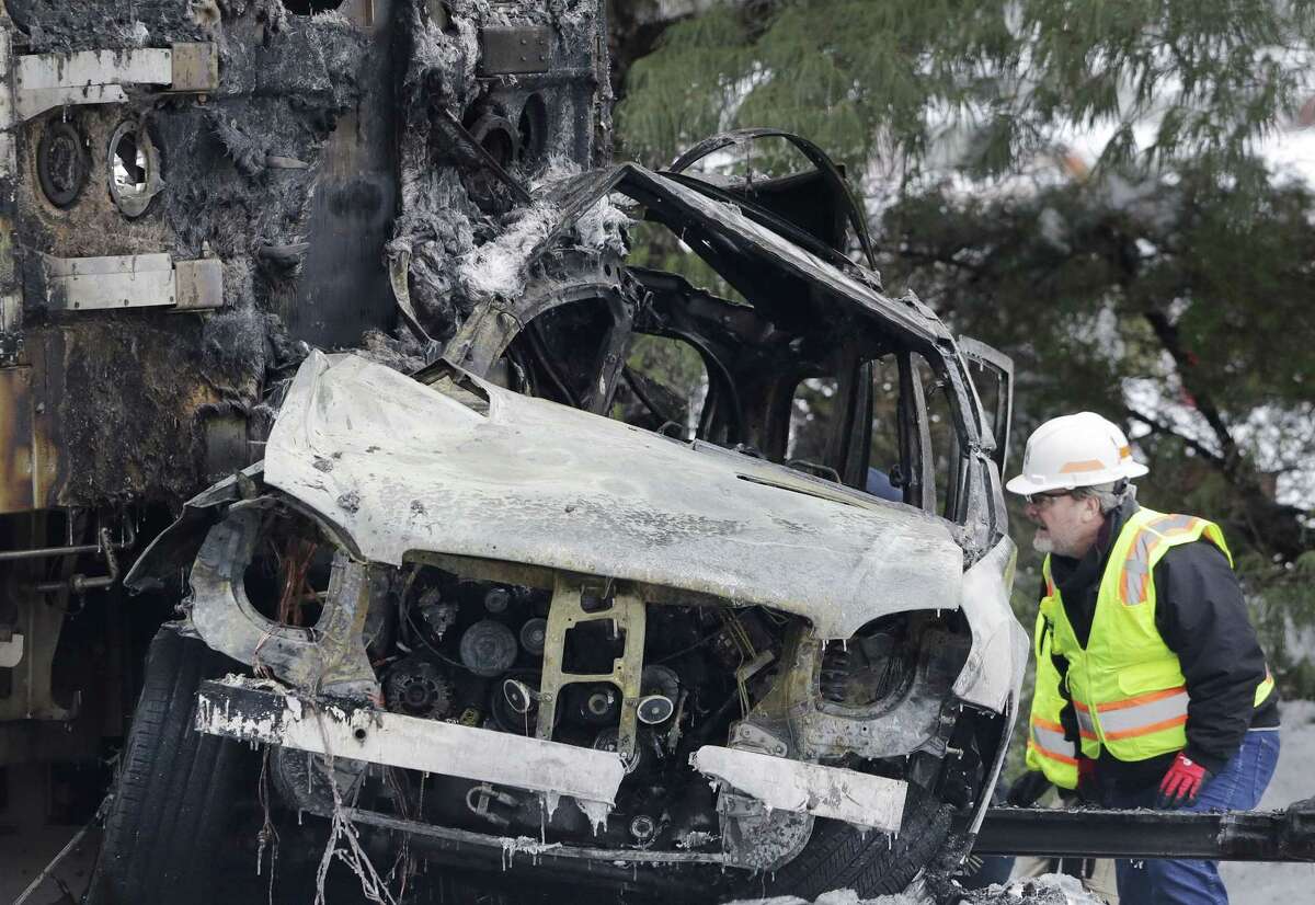 An official looks at a SUV that was crushed and burned at the front of a Metro-North Railroad train Wednesday, Feb. 4, 2015, in Valhalla, N.Y. Five train passengers and the SUVís driver were killed in Tuesday eveningís crash in Valhalla, about 20 miles north of New York City. Authorities said the impact was so forceful the electrified third rail came up and pierced the train. (AP Photo/Mark Lennihan)