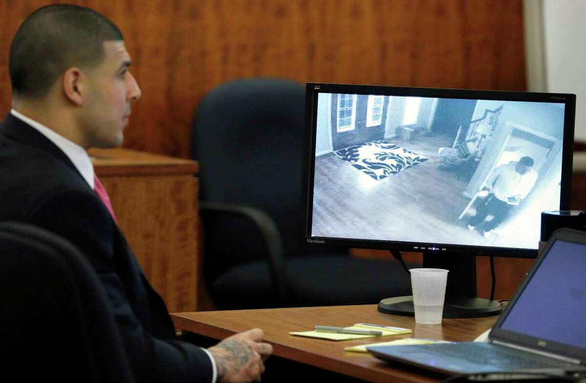 Former New England Patriots NFL football player Aaron Hernandez looks on as a still image from a June 17, 2013 surveillance video from his home is displayed on a monitor during his murder trial on April 2, 2015, in Fall River, Mass.