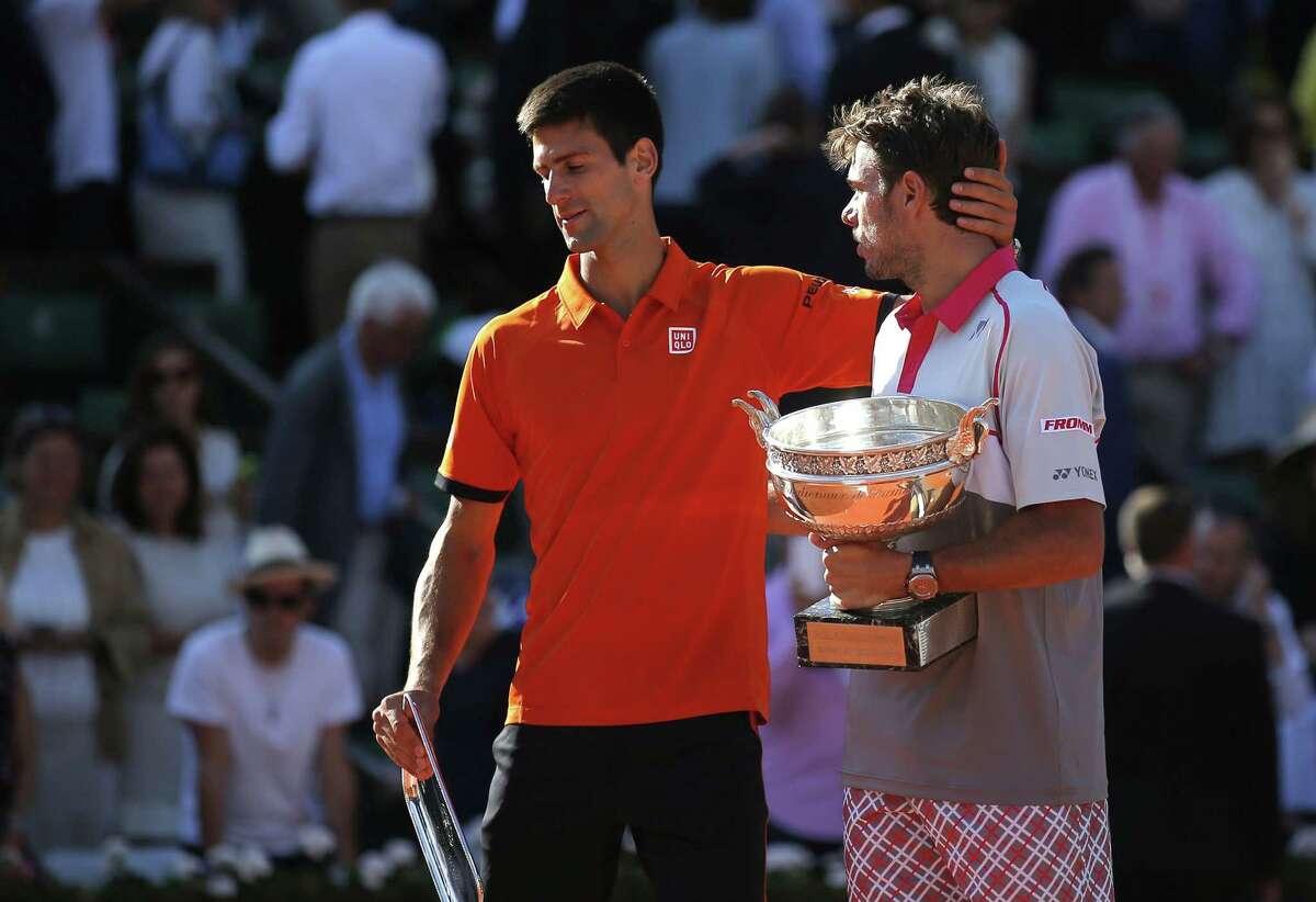 Switzerland’s Stan Wawrinka, right, holds the cup while Serbia’s Novak Djokovic leaves the ceremony after their men’s final match at the Roland Garros stadium on Sunday. Wawrinka won 4-6, 6-4, 6-3, 6-4.
