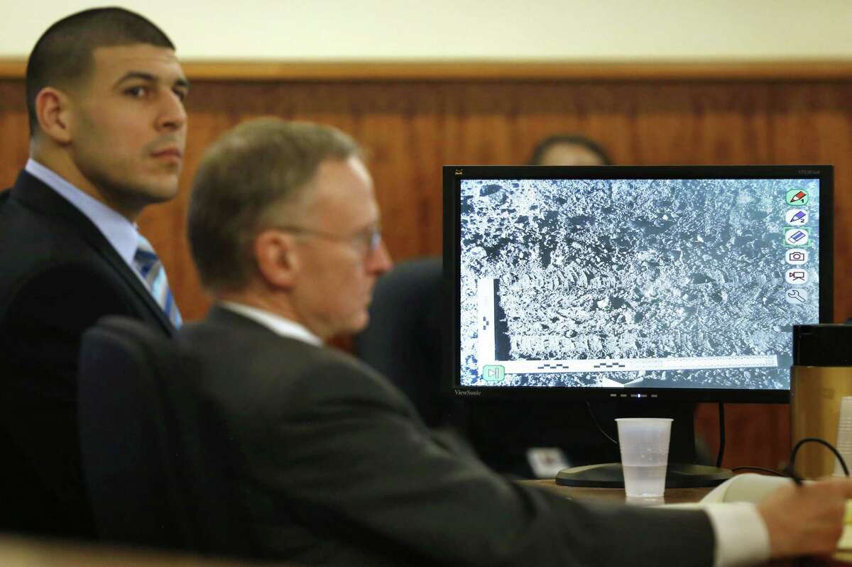 Former New England Patriots football player Aaron Hernandez, left, sits with his defense attorney Charles Rankin, center, as a photograph of tire marks is displayed on a monitor during Hernandez’s murder trial Thursday in Fall River, Mass.