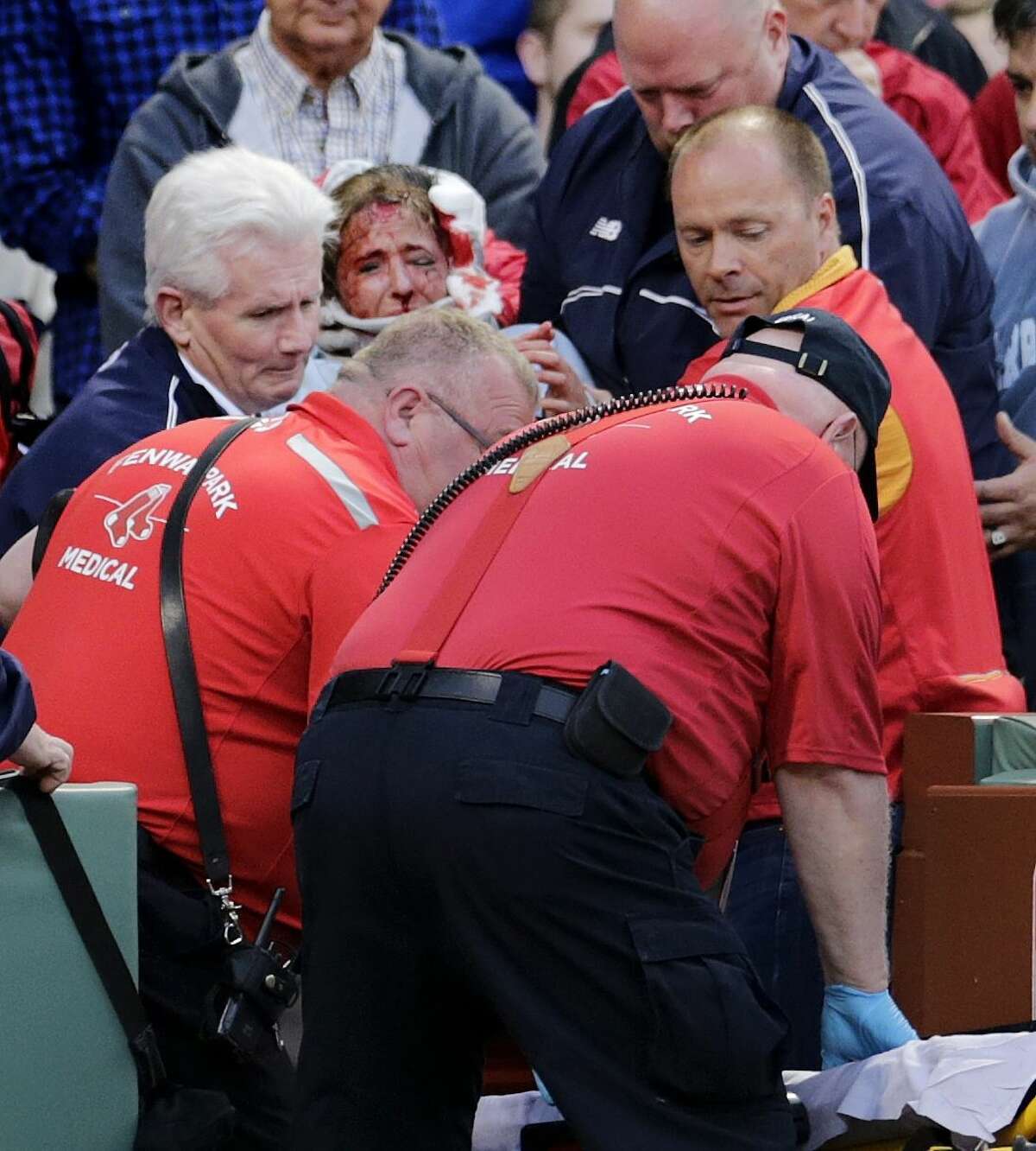 A fan, who was hit in the head with a broken bat by the Oakland Athletics’ Brett Lawrie, is helped from the stands during Friday night’s game at Fenway Park in Boston.