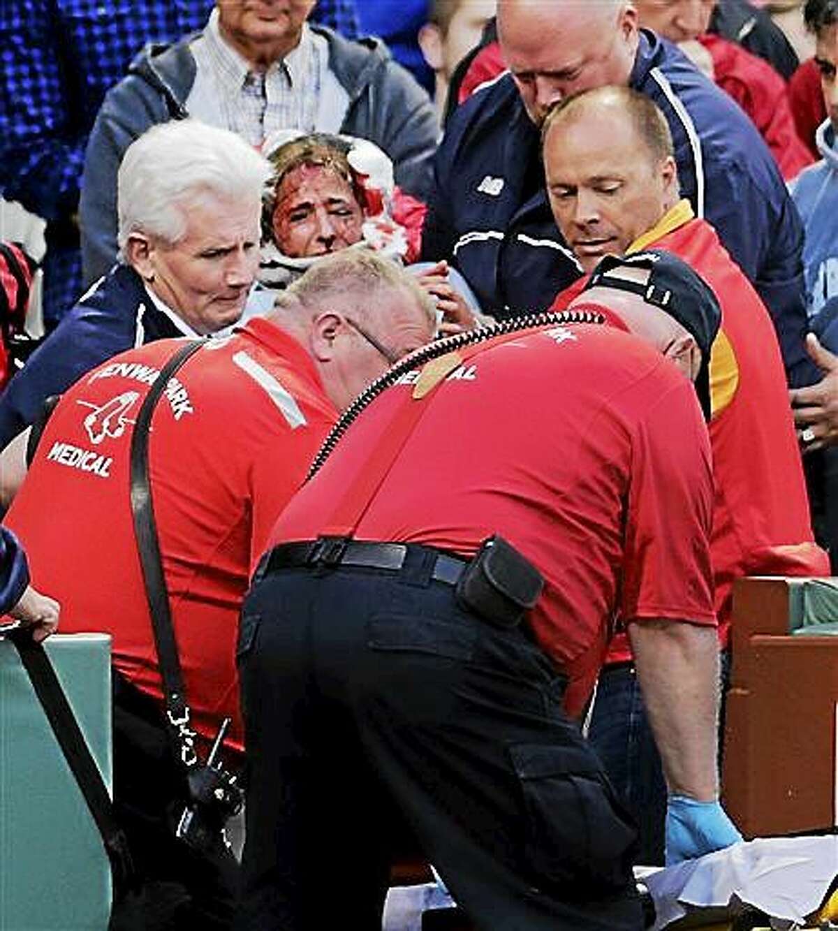 A fan, who was accidentally hit in the head with a broken bat by Oakland Athletics' Brett Lawrie, is helped from the stands during a baseball game against the Boston Red Sox at Fenway Park in Boston, Friday, June 5, 2015. The game was stopped while they wheeled her down the first base line. (AP Photo/Charles Krupa)