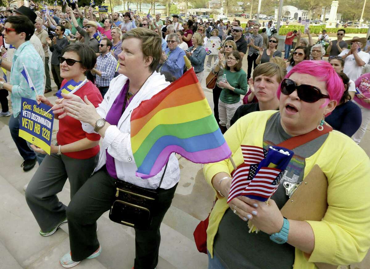In this March 31, 2015 file photo, Barbara Hall, right, of Little Rock, joins others at a rally against a new religious objections law outside the Capitol in Little Rock, Ark. The national focus on whether new religious objections laws in Indiana and Arkansas could be used to discriminate against gays and lesbians has boosted efforts for broader civil rights law protections in those and other states. (AP Photo/Danny Johnston, File)