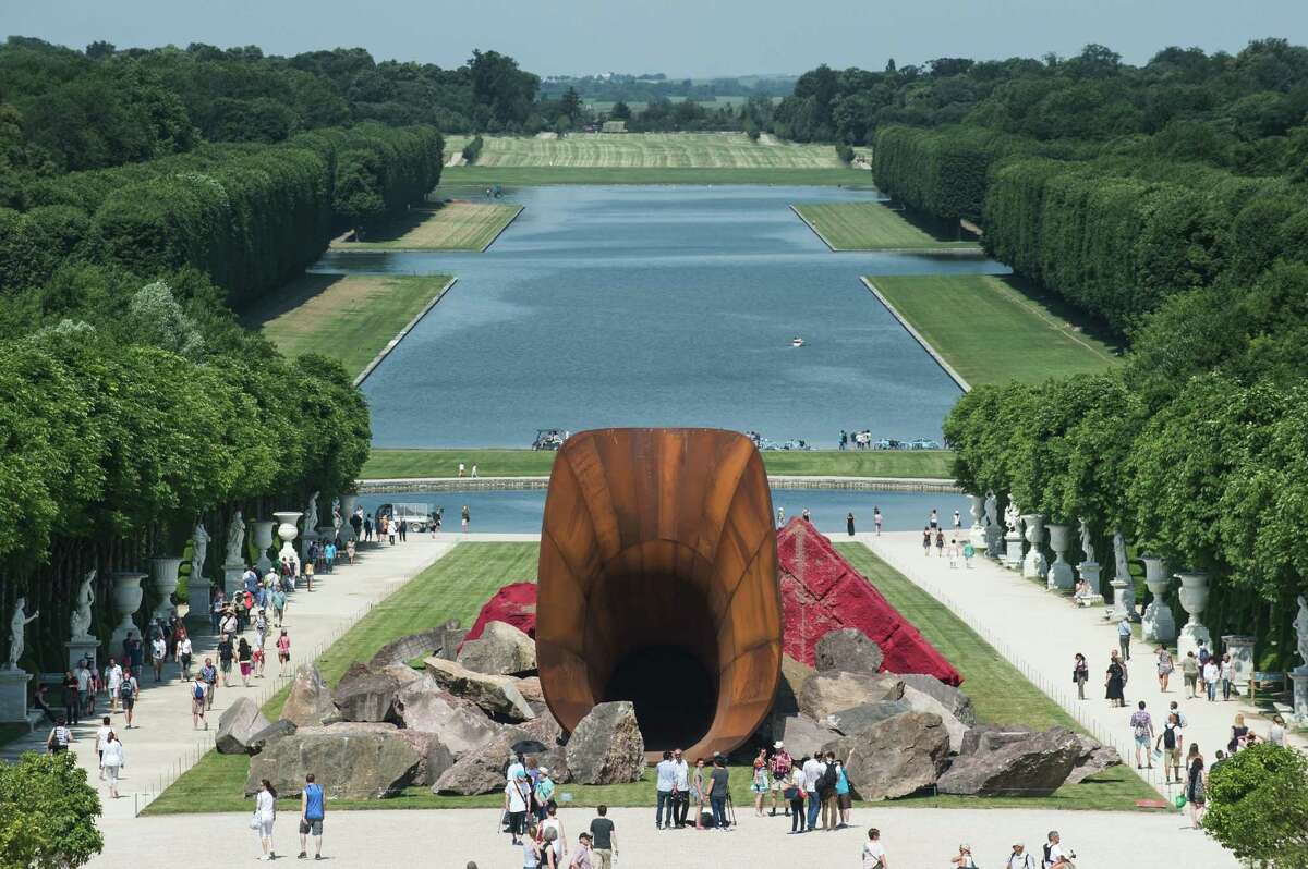 Visitors are walking alongside "Dirty Corners" by British artist Anish Kapoor in the gardens of the Chateau de Versailles outside Paris, France, Friday, June 5, 2015. Is that new sculpture in the gardens of Versailles a massive tuba? Or is it supposed to represent Marie Antoinetteís private parts? Artist Anish Kapoor isnít saying exactly what the centerpiece of his latest installation, called ìDirty Corner,î represents. (AP Photo/Kamil Zihnioglu)