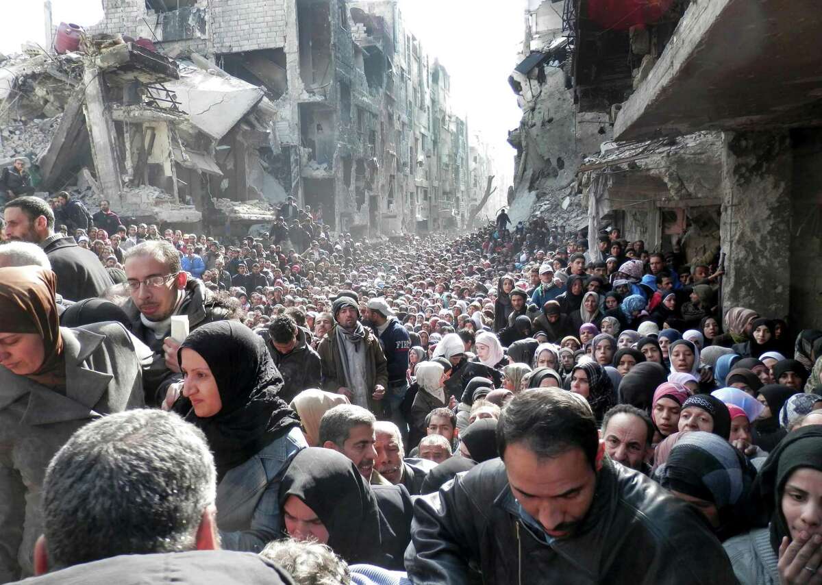 This picture taken on Jan. 31, 2014, and released by the United Nations Relief and Works Agency for Palestine Refugees (UNRWA), shows residents of the besieged Palestinian camp of Yarmouk, queuing to receive food supplies, in Damascus, Syria.
