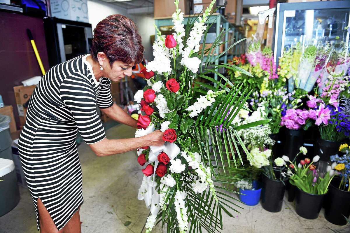 Lisa Piasecki, owner of Flowers by Lisa, arranges a funeral spray in the back of an adjoining warehouse on Hemingway Avenue in East Haven Tuesday, after a fire damaged her shop.
