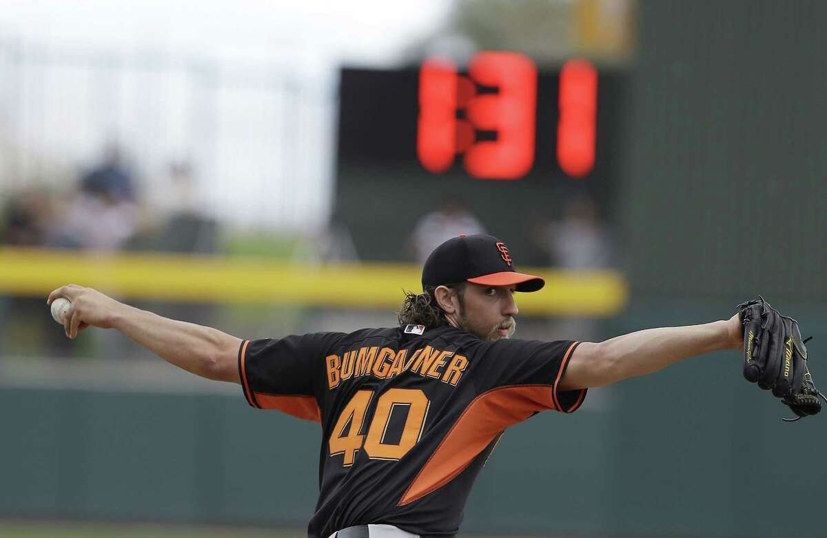 San Francisco Giants pitcher Madison Bumgarner warms up before the bottom of the second inning against the Oakland Athletics as a clock counts down time between innings Tuesday in Mesa, Ariz.