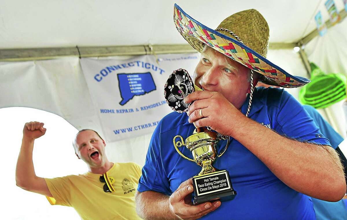 Seymour Land Trust President Alex Danka pretends to bite the plastic taco on the top of the championship trophy at the Cinco de Mayo Elected Officials’ Taco-Eating Contest Tuesday, after downing 14 tacos to benefit TEAM, Inc.’s Meals on Wheels program.