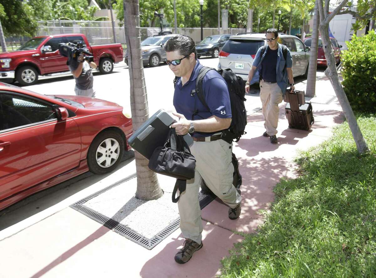 Federal Bureau of Investigation agents leave the offices of the Confederation of North, Central America and Caribbean Association Football (CONCACAF,) Wednesday, May 27, 2015, in Miami Beach, Fla. Swiss prosecutors opened criminal proceedings into FIFA's awarding of the 2018 and 2022 World Cups, only hours after seven soccer officials were arrested Wednesday pending extradition to the U.S. in a separate probe of "rampant, systemic, and deep-rooted" corruption. (AP Photo/Wilfredo Lee)