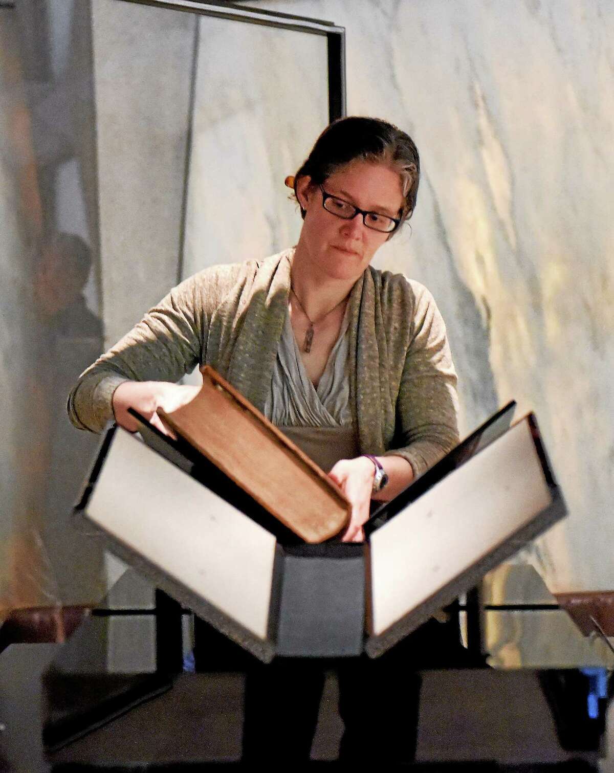 Rebecca Hatcher, the preservation coordinator librarian at the Beinecke Rare Book and Manuscript Library, removes the two-volume Gutenberg Bible from its locked and alarmed glass enclosure, swaddling it in a protective plastic box for the trip to Chapel Street.