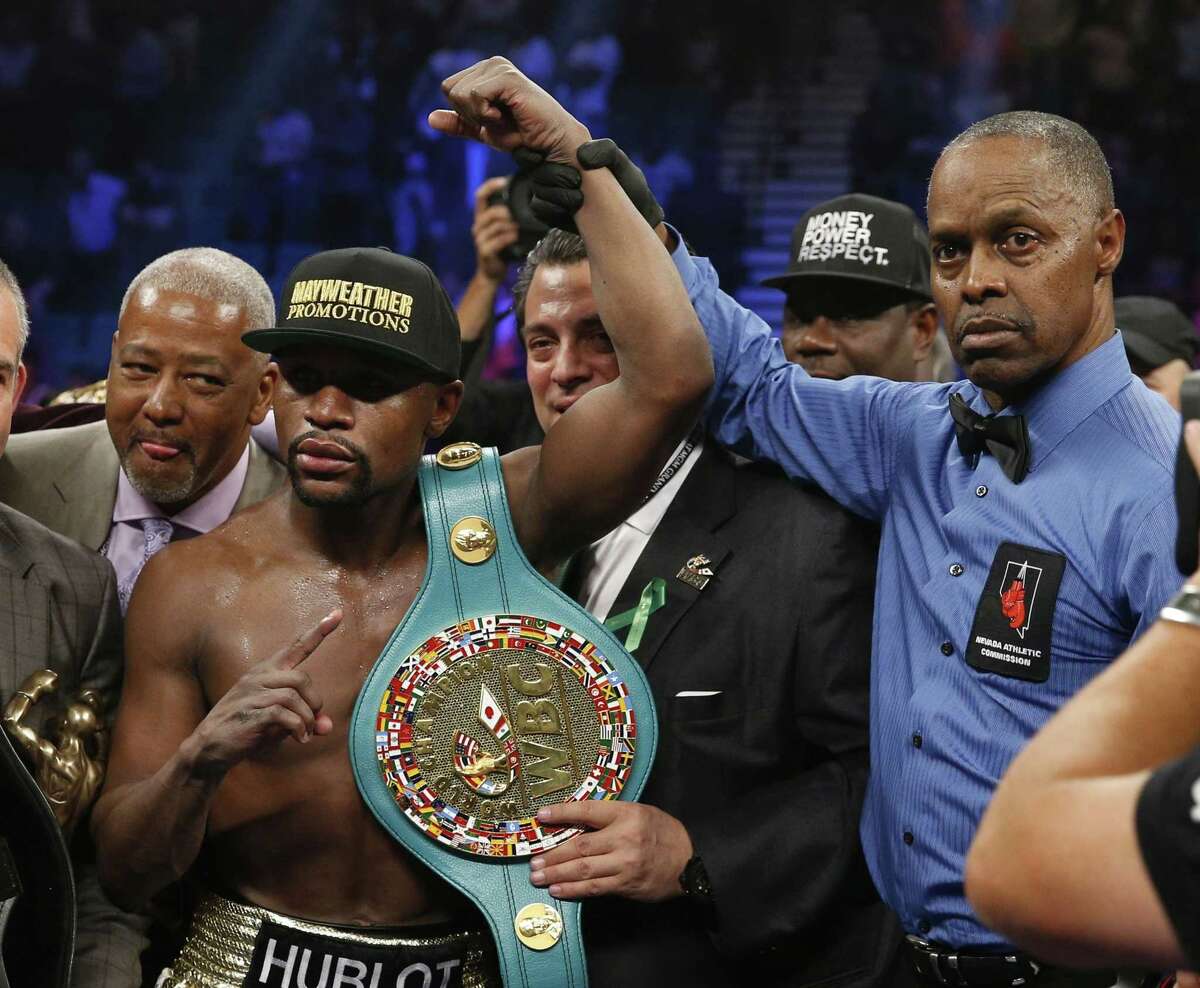 Floyd Mayweather Jr., left, holds up the title belt next to referee Kenny Bayless after his win against Manny Pacquiao on Saturday in Las Vegas.
