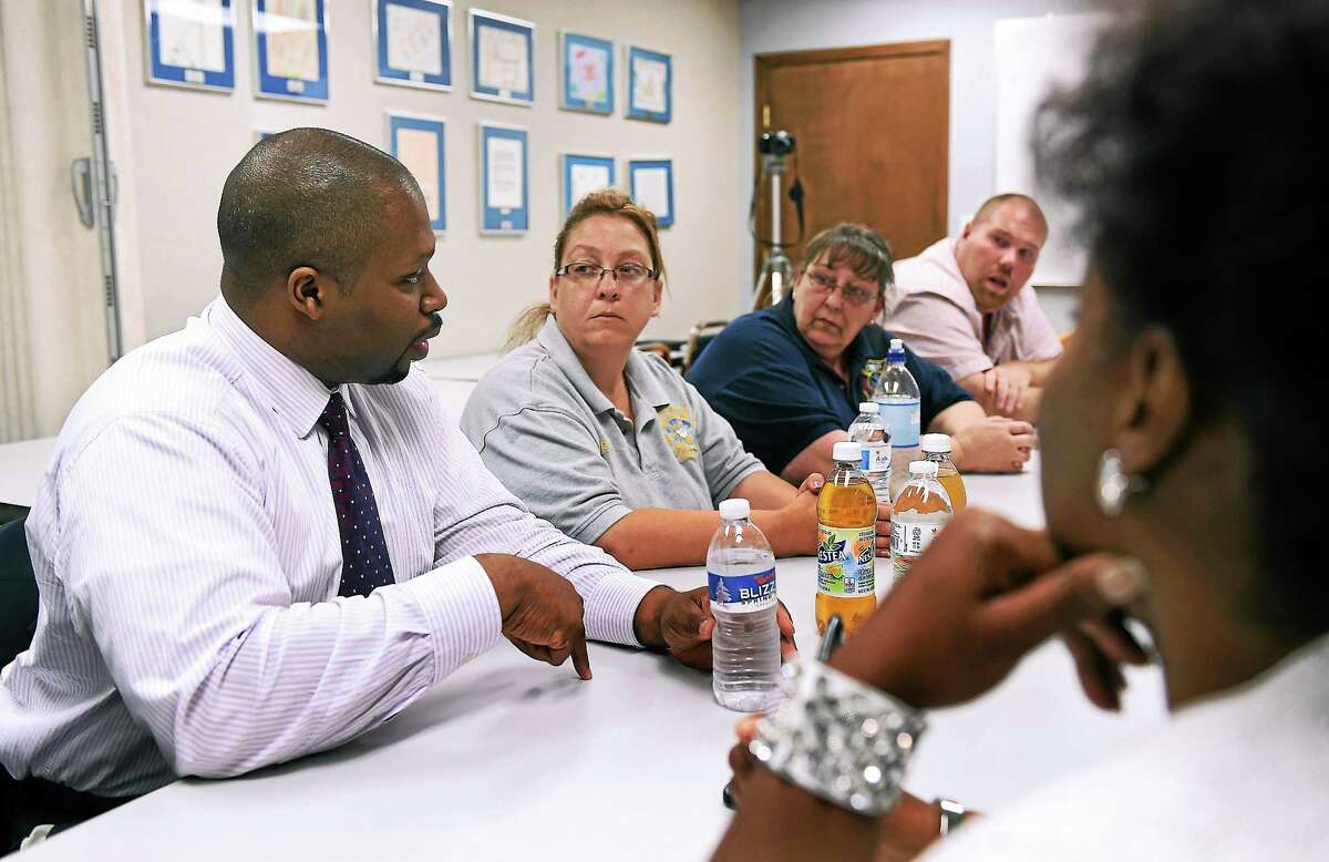 State Senator Gary Holden-Winfield, left, talks with current CMED employees and several who were recently laid-off during a meeting Monday at the C.W.A. Local 1298 Union headquarters in Hamden. On the right, in foreground is State Rep. Robyn Porter (94th district). July 14, 2014. pcasolino@newhavenregister.com