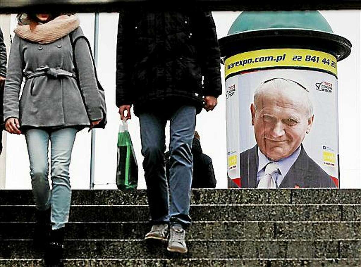 People are walking by a poster marking 10 years since the death of Polish-born Pope John Paul II.
