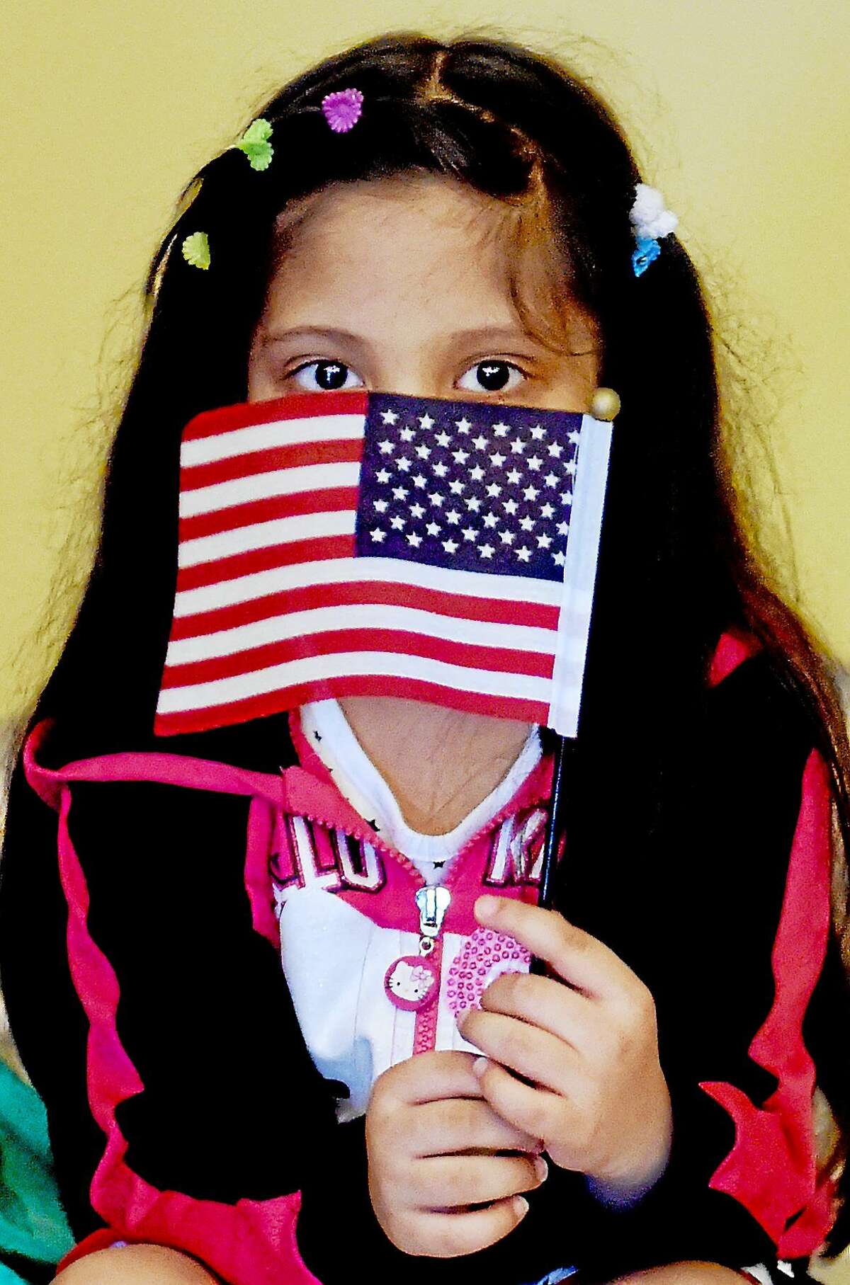 PETER HVIZDAK — NEW HAVEN REGISTER An unidentified girl holds a flag given to those who became citizens Monday.