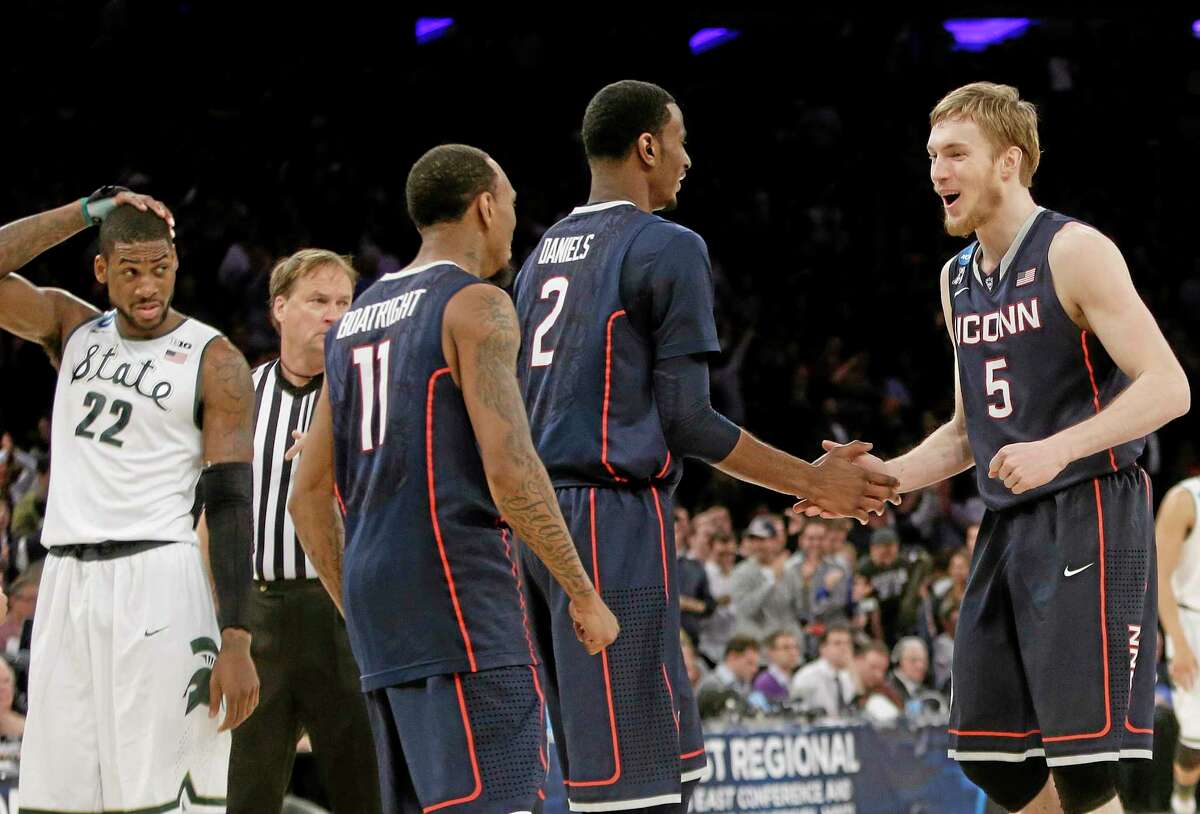 Connecticut's Niels Giffey (5), of Germany, celebrates with teammates DeAndre Daniels (2) and Ryan Boatright (11) as Michigan State's Branden Dawson (22) watches during the second half of a regional final in the NCAA college basketball tournament on Sunday, March 30, 2014, in New York. Connecticut won the game 60-54. (AP Photo/Frank Franklin II)