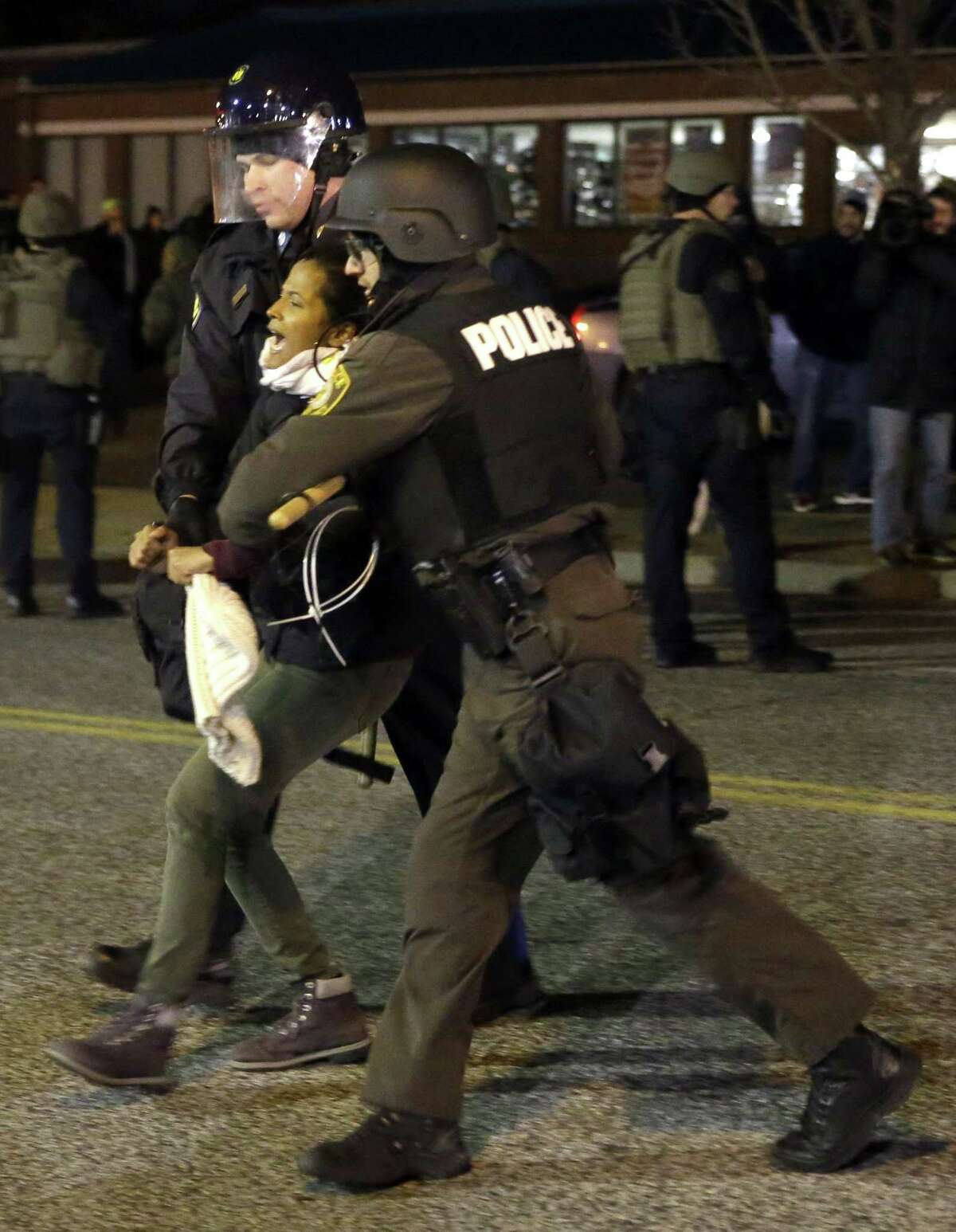A protester is taken into custody Friday, Nov. 28, 2014, in Ferguson, Mo. Several protesters have been taken into custody during a demonstration outside the police department. Tensions escalated late Friday during an initially calm demonstration after police said protesters were illegally blocking West Florissant Avenue. (AP Photo/Jeff Roberson)