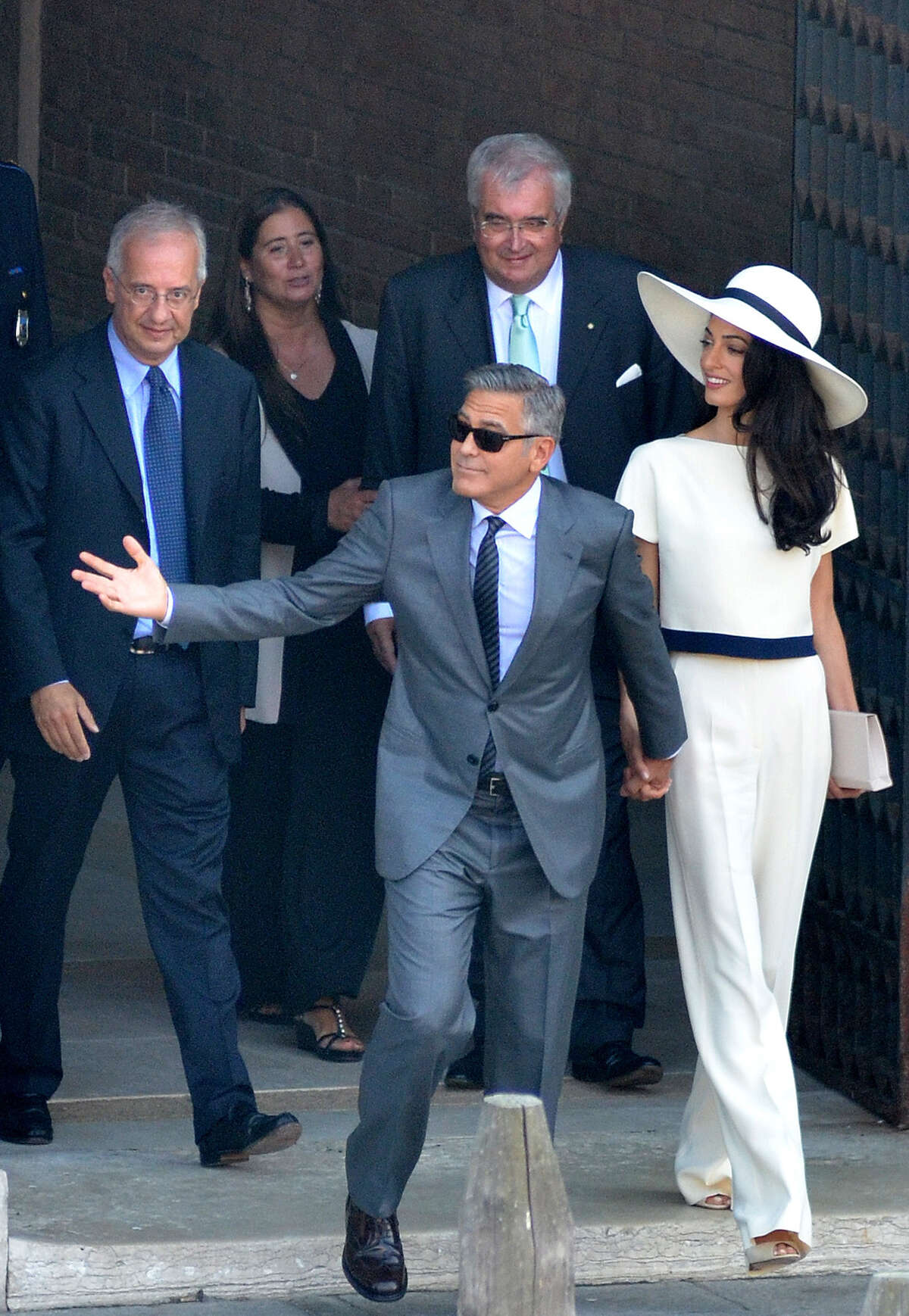 George Clooney and his wife Amal Alamuddin leave the city hall after their civil marriage ceremony performed by former Rome's mayor Walter Veltroni, left, in Venice, Italy, Monday, Sept. 29, 2014. George Clooney married human rights lawyer Amal Alamuddin Saturday, the actor's representative said, out of sight of pursuing paparazzi and adoring crowds. (AP Photo/Luigi Costantini)