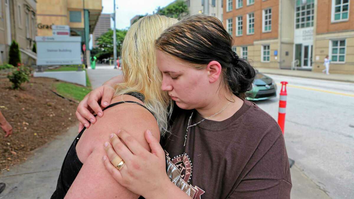 Alecia Phonesavanh, right, is hugged by her mother, Marlene Haygood, left, on Thursday, May 30, 2014 in Atlanta as they talk about an incident in which Phonesavanh's 19-month-old boy was critically injured when a police device was tossed into his bed Wednesday morning in Habersham County by a SWAT team in search of a drug suspect. Phonesavanh said there is no way officers should not have known they were children in the house. Habersham County Sheriff Joey Terrell said the officers were looking for a suspect who may have been armed and followed proper procedure by using the device. (AP Photo/Atlanta Journal-Constitution, John Spink)