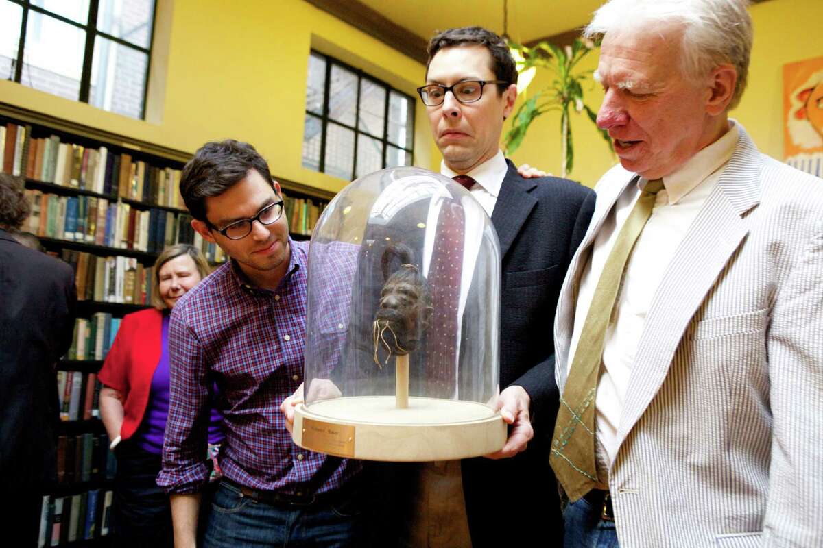 Josh Foer, left, and Jack Hitt, right, conspired to find a shrunken head as a farewell gift to Will Baker, center, departing executive director of The Institute Library. (Photo by Judy Sirota Rosenthal).
