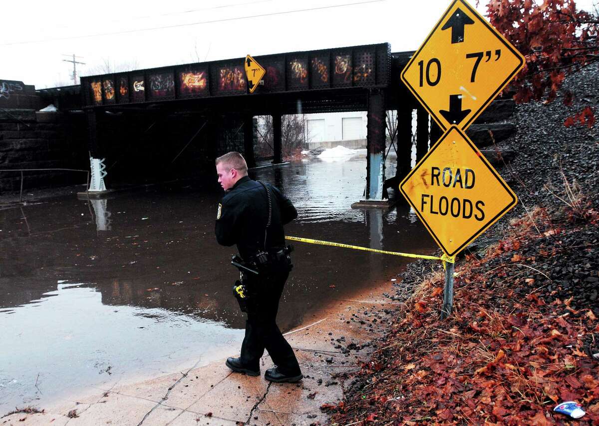 (Arnold Gold ó New Haven Register) West Haven Police Officer Justin Standish puts police tape across a flooded portion of Washington Ave. in West Haven after a downpour on 1/11/2014.