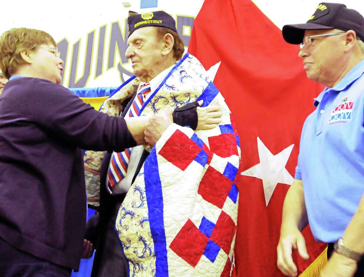 Nancy Olson of Hamden, a member of the Quilts of Valor Foundation, left, gives Joseph Myjak of Hamden, a World War II U.S Army Ranger veteran a quilt, center, during the Hamden Veterans Awareness Day May 23, 2014 at Quinnipiac Universty. Standing at far right is David Lewis of Hamden, a U.S. Army and U.S. Navy veteran, who also received a quilt.