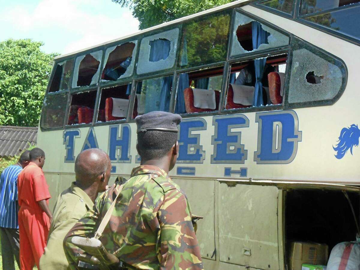 A Kenyan police officer with civilians watch the Taheed Bus at the Lamu Police Station, Saturday, July 19, 2014. The Kenya Red Cross says seven people have been killed after gunmen attacked a bus along the Kenyan coast where previous attacks had left 87 people dead. The humanitarian group said Saturday the attack Friday night came at Corner Mbaya, 5 kilometers (3 miles) from the coastal town of Witu. Al-Qaida-linked al-Shabab militants from Somalia claimed responsibility for the attack. (AP Photo)