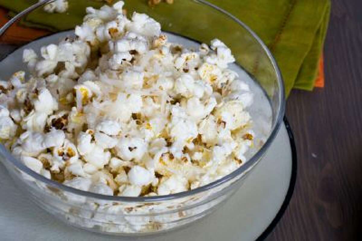 Popcorn with finely grated parmesan cheese is shown served in a bowl.