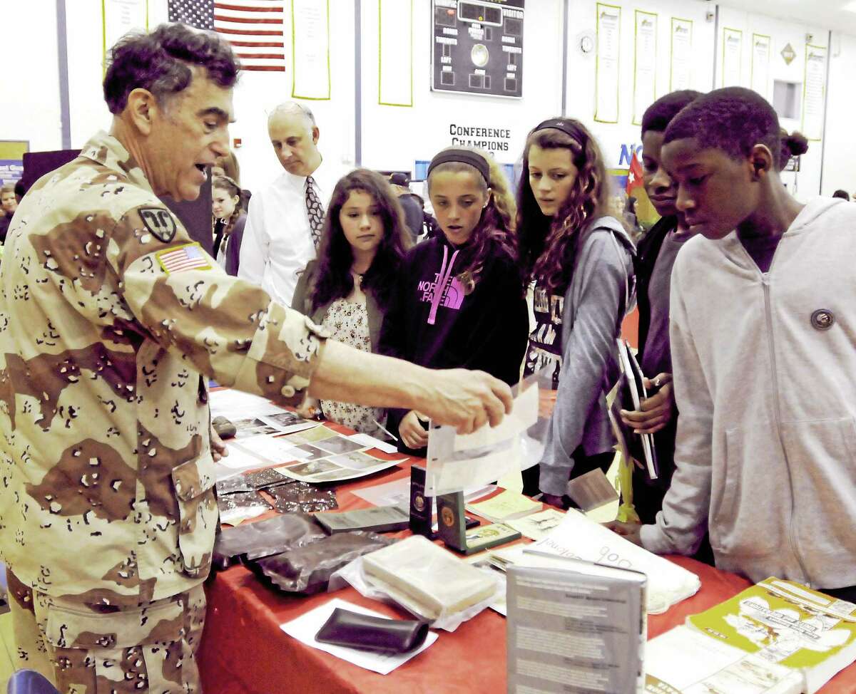 Retired Army Lt. Col Robert Gualtieri of Hamden, left, a veteran of Desert Shield and Desert Storm, shows Hamden Middle School students some of the items he had when he served in the Army during the Veterans Awareness Day Friday at Quinnipiac University in Hamden.