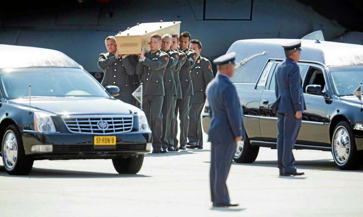 Pallbearers carry a coffin towards a hearse during a ceremony to mark the return of the first bodies, of passengers and crew killed in the downing of Malaysia Airlines Flight 17, from Ukraine at Eindhoven military air base, Netherlands, Wednesday, July 23, 2014. After being removed from the planes, the bodies are to be taken in a convoy of hearses to a military barracks in the central city of Hilversum, where forensic experts will begin the painstaking task of identifying the bodies and returning them to their loved ones. (AP Photo/Phil Nijhuis)