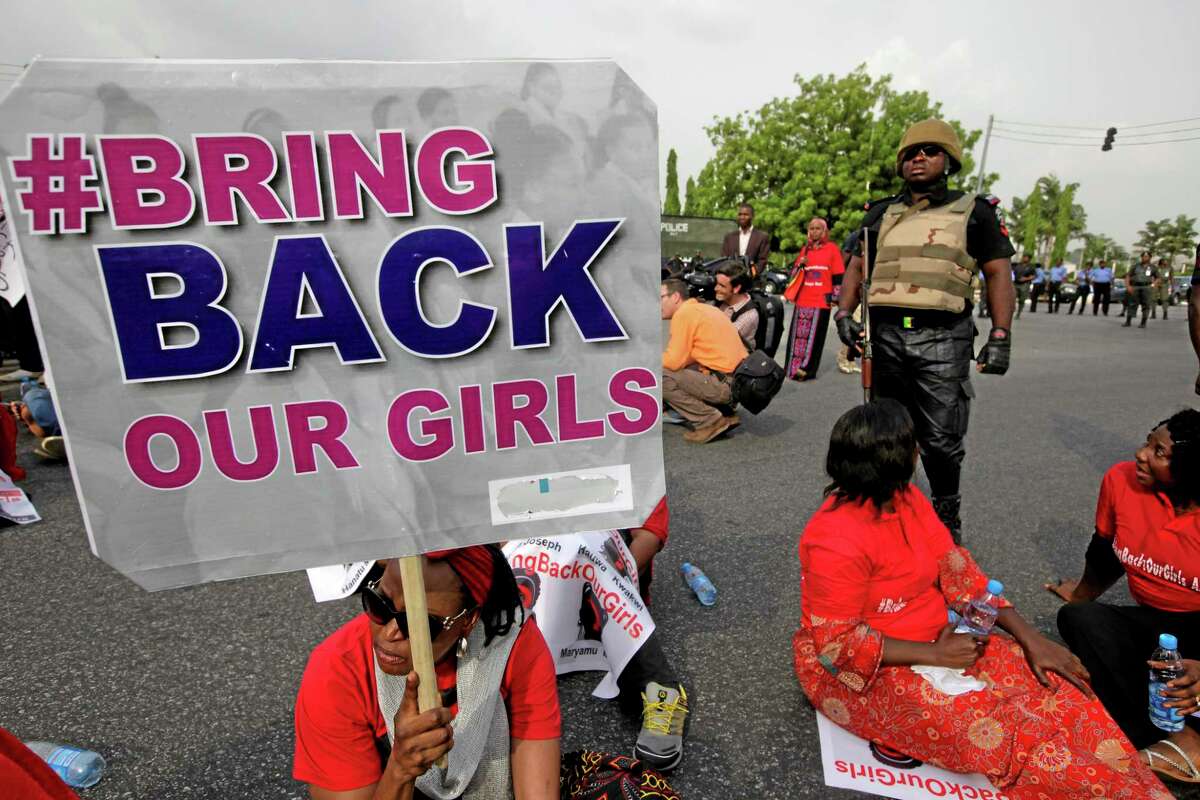 A police officer stands guard as people attend a demonstration calling on the government to rescue the kidnapped girls of the government secondary school in Chibok, in Abuja, Nigeria, Thursday, May 22, 2014. Scores of protesters chanting "Bring Back Our Girls" marched in the Nigerian capital Thursday as many schools across the country closed to protest the abductions of more than 300 schoolgirls by Boko Haram, the government's failure to rescue them and the killings of scores of teachers by Islamic extremists in recent years. (AP Photo/Sunday Alamba)